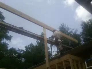 Carpenter setting a ridge beam over a new addition frame — Ice Dam Removal by Roofing Brothers in Tallahassee
