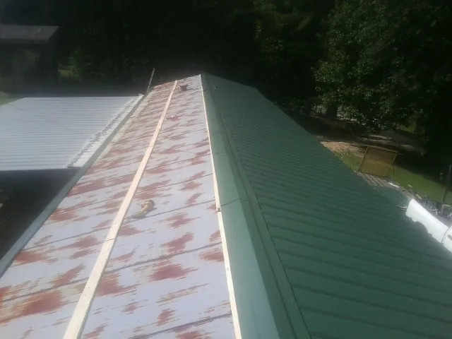Old rusted panels beside newly installed green metal roofing — Wind Damage Roof Repair by Roofing Brothers in Tallahassee