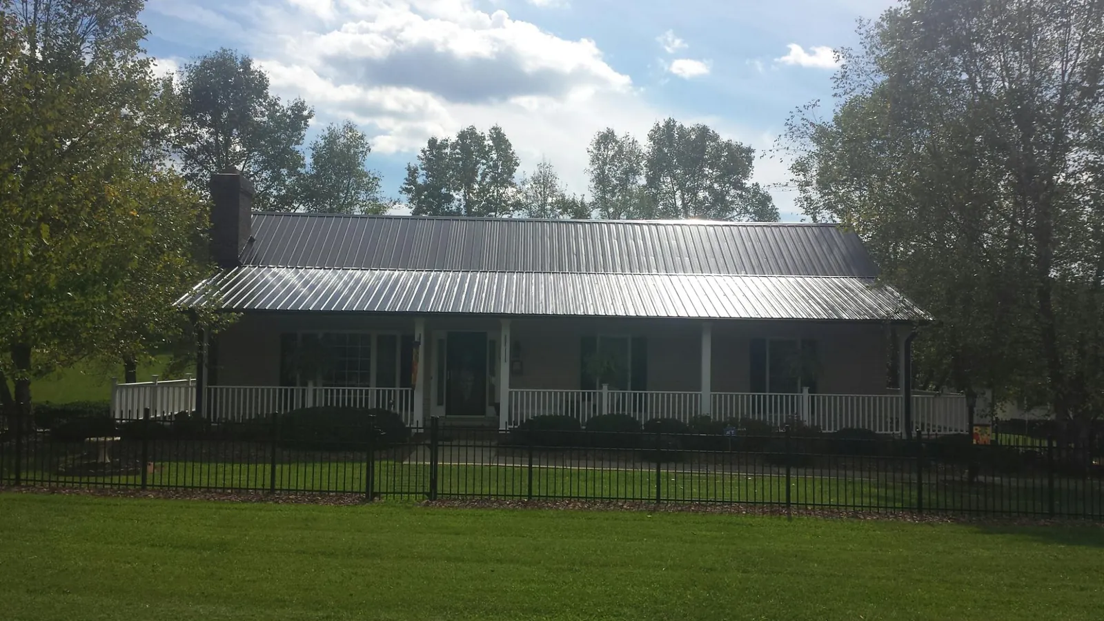 Gray metal roof on a brick ranch with a full width front porch — Gutter Guard Installation work by our crew in Tallahassee