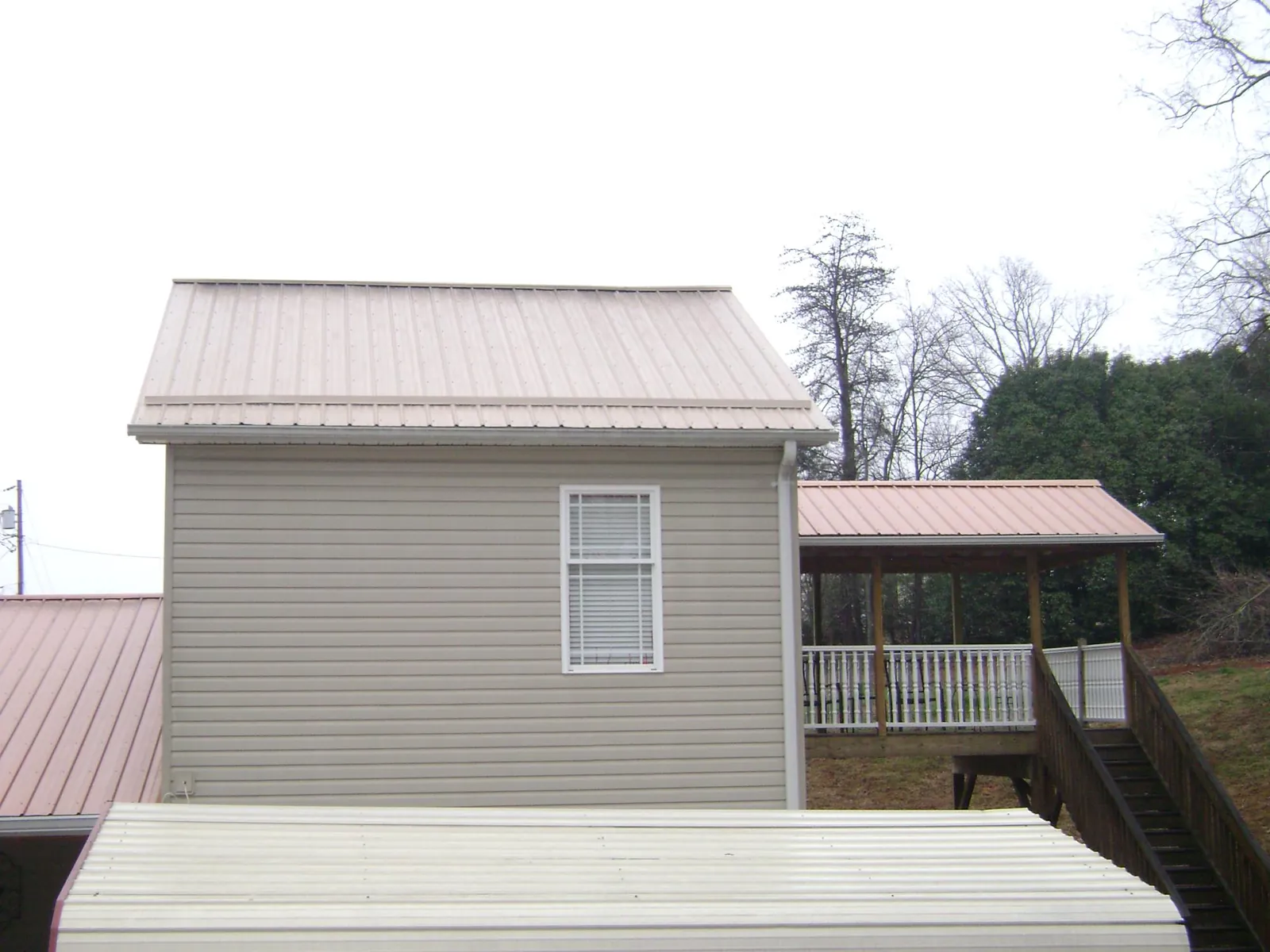 Tan metal roofs on a two story addition and attached porch, from a Roof Replacement job in Tallahassee